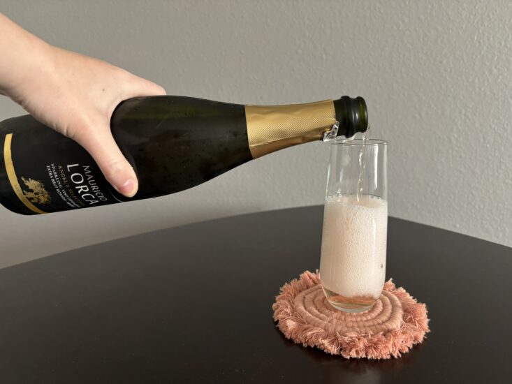 pouring bottle of sparkling rose wine into glass