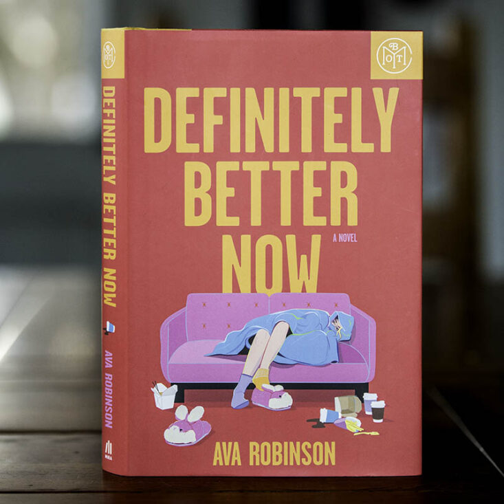 December Book of the Month pick Definitely Better Now by Ava Robinson sits on a tabletop